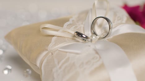 close up of wedding rings for bride and groom on small decorated cushion 2