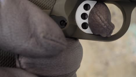 primer plano de una mano enguantada apretando el gatillo de un arma