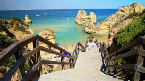 beautiful fashion girl in a dress walking by the steps of lagos, algarve.