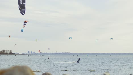 Kitesurf-Deslizándose-Sobre-El-Agua-En-La-Costa-Nórdica-De-Estonia,-Con-La-Ciudad-Capital-De-Tallin-Como-Telón-De-Fondo