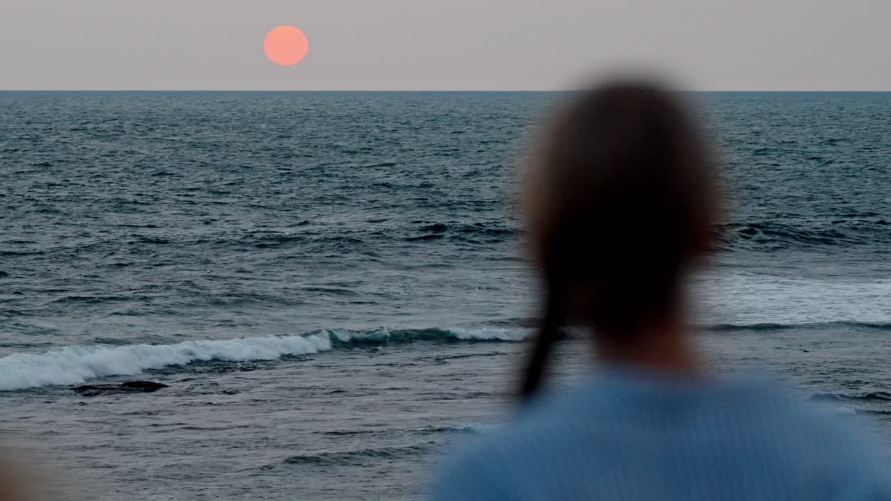 A serene moment in Galle, Sri Lanka, as a woman gazes at the vast ocean during a breathtaking sunset.