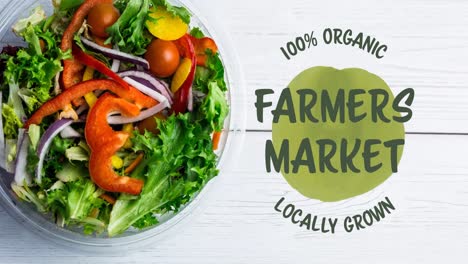 animation of farmers market text in green over fresh organic vegetable salad in bowl on wood