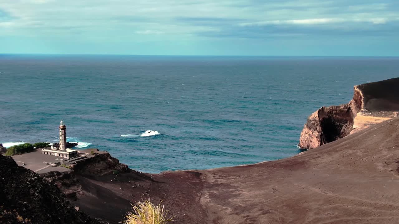 Stunning panoramic view of the Capelinhos Lighthouse on Faial Island, standing amid volcanic ash cliffs and the vast Atlantic Ocean