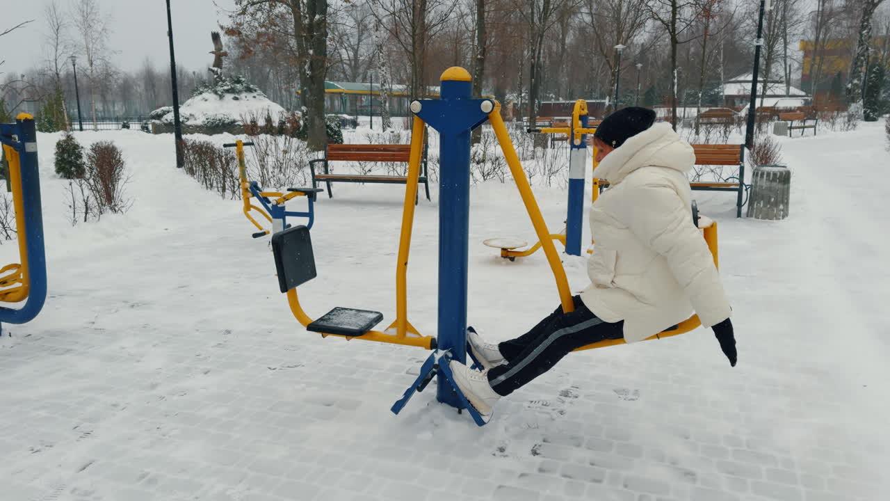 Senior woman exercising sitting on the simulator. Aged lady doing sport outdoors on snowing weather.