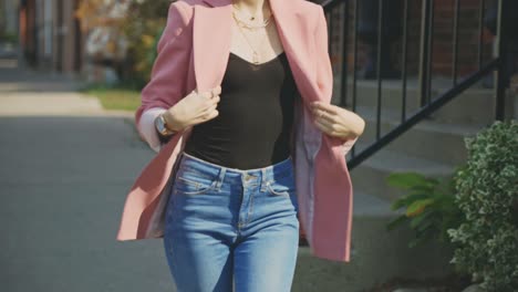 petite woman with her tight jeans and pink suit walking on the sidewalk during daytime