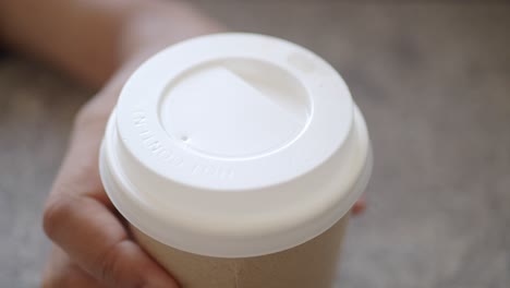 mano con una taza de café desechable