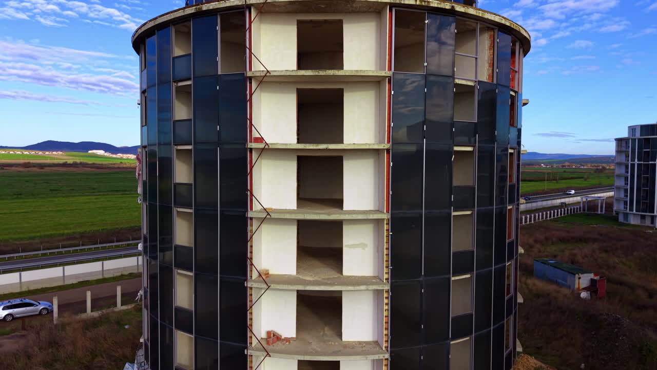 Costruzione di un edificio a più piani di forma cilindrica. Traffico autostradale sullo sfondo. Prospettiva aerea