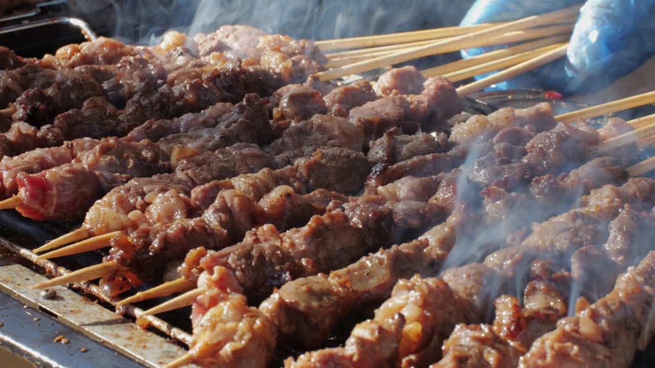 Pork meat skewer on fire, Mutton barbecue close-up. Fried meat for kebab. Cooking grilled meat beef chicken lamb BBQ . Kebab on grill. Chinese street local market with traditional food. Asian fast food.