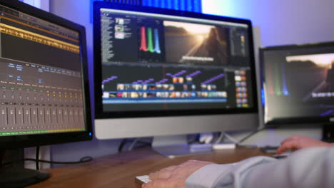 un hombre que trabaja como editor en un estudio de medios editando video y audio en múltiples pantallas