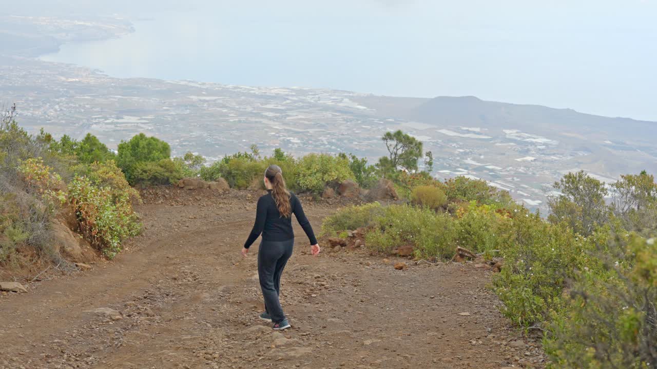 vista sobre la costa norte de tenerife, chica en chándal caminando por el sendero, en cámara lenta