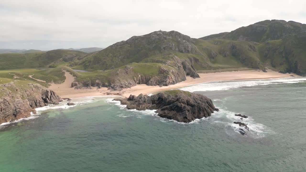 fotos aéreas de la playa rodeada de exuberantes acantilados verdes y colinas onduladas, destacando la belleza natural del paisaje
