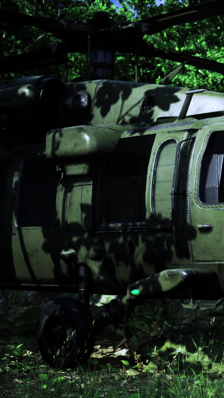 Military helicopter on the ground surrounded by trees in forest setting