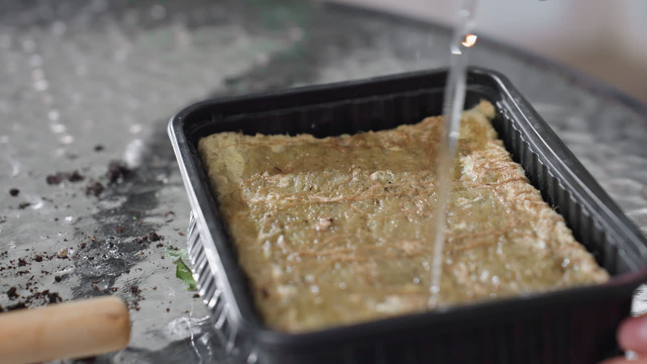 Hand sprinkling water from narrow spout onto fibrous growing mat in black tray on textured glass table scattered soil debris nearby indoor gardening routine nurturing seedlings vibrant