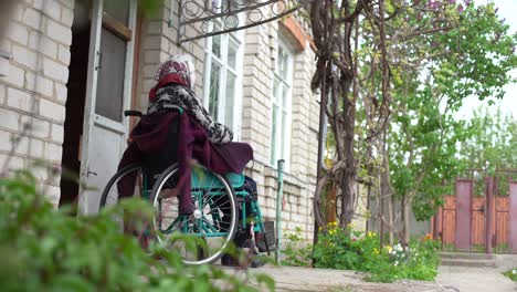 Old-lonely-woman-sitting-in-a-wheelchair-near-the-window-in-his-house