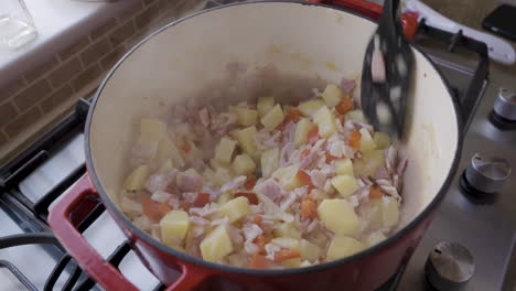 cooking potatoes, ham, and red peppers in a pot on the stove top
