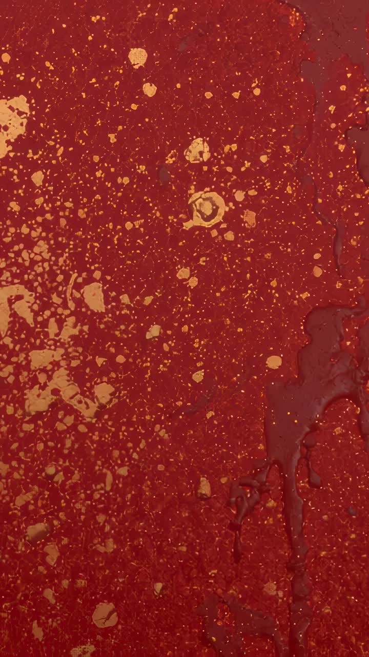 Vertical video: Shifting camera studying red panel in studio, revealing metallic gold splatters