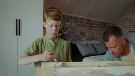 father and son painting a wooden table together