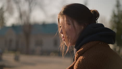 primer plano de una chica con un abrigo marrón, con el cabello cubriendo parcialmente su cara. parece triste y perdida en los pensamientos, su expresión refleja un profundo sentido de tristeza y agitación emocional