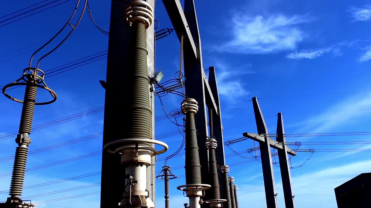 Electrical Substation with High Voltage Power Lines Against Blue Sky