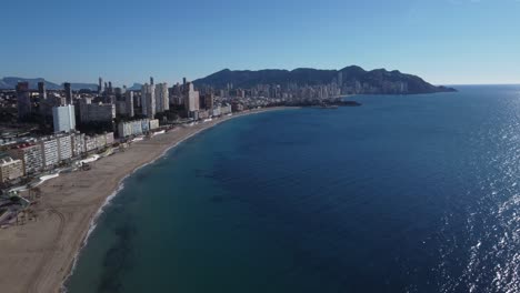 Vista-Aérea-De-La-Bahía-Con-La-Playa-De-Levante-Y-El-Paisaje-Urbano-General-De-Benidorm-En-El-Mar-Mediterráneo-En-La-Provincia-Española-De-Alicante