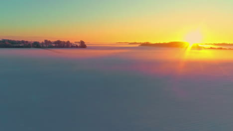 aerial flyover sea of clouds with golden sun rays in background during dusk in the air