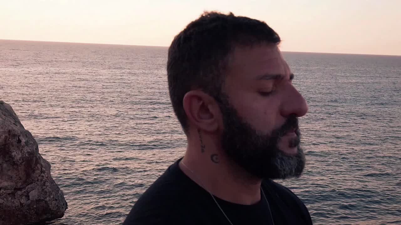 hombre barbudo meditando junto al mar