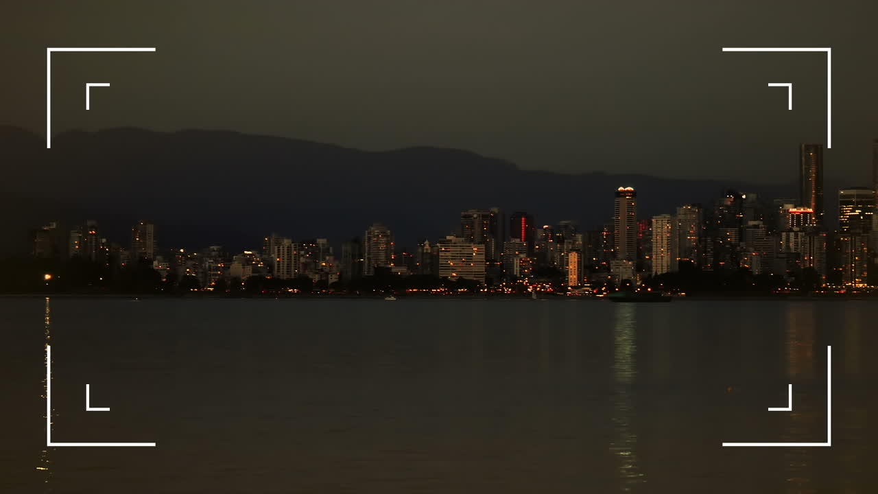 Digital camera interface against view of sea and cityscape at night