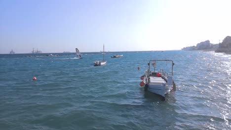 Boot-Im-Vordergrund-Mit-Einem-Kitesurfer,-Der-Die-Wellen-In-Kabbeligem-Wasser-Im-Hintergrund-Reitet