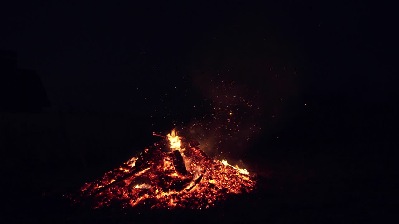 Bright sparks from a fire. A male farmer burns branches at night. Fire flame. Outdoor fireplace. Burning of firewood. Natural background