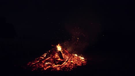 bright sparks from a fire. a male farmer burns branches at night. fire flame. outdoor fireplace. burning of firewood. natural background