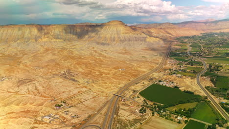 highways separating dry sandy deserted land from a beautiful oasis town at the foot of mountain. heavy clouds throwing shadows on the ground. top view.