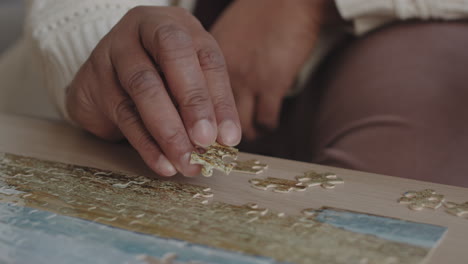 steadicam of hand of cropped unrecognizable person sitting at coffee table, adding piece to jigsaw