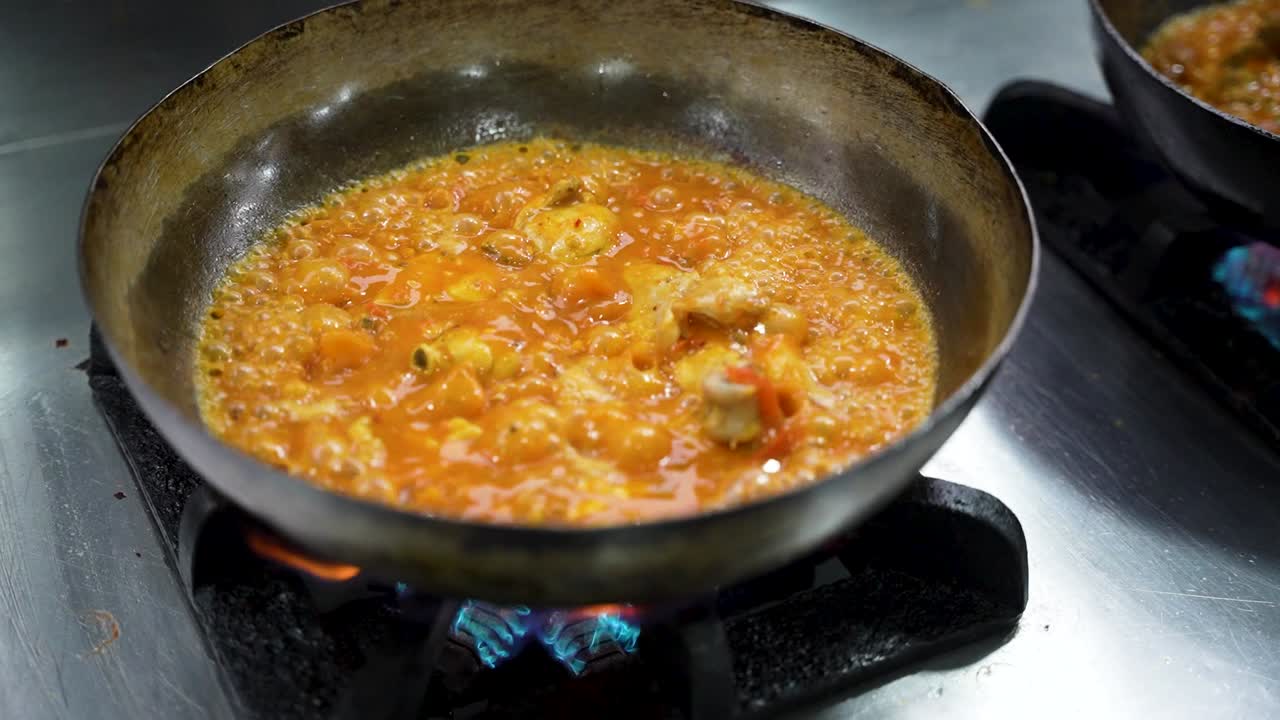 Chicken cooking in a rich, bubbling tomato-based curry for Peshawari karahi in Pakistan