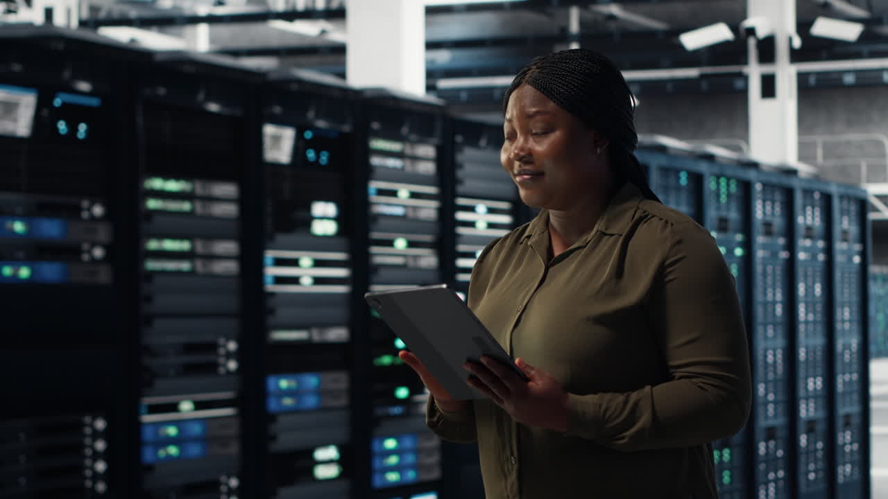 Engineer with tablet walks through data center server rows