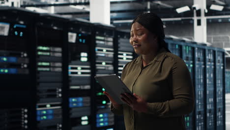 engineer with tablet walks through data center server rows