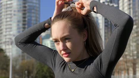 young athletic woman tying up hair during morning run