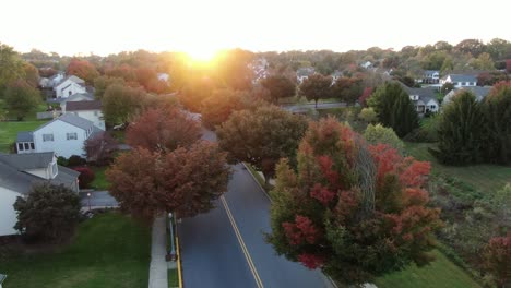 slow aerial turn reveals fall colors during crisp autumn sunset, locust and maple trees line streets and homes