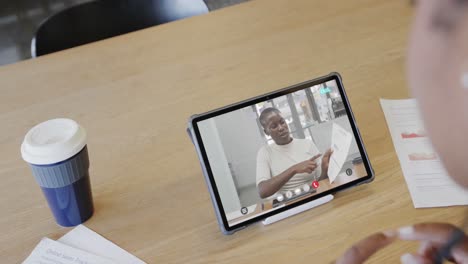 caucasian businesswoman on tablet video call with african american male colleague on screen