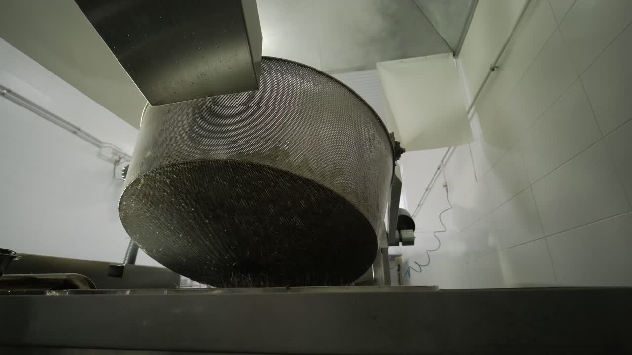 producción de papas fritas y bocadillos. máquina industrial de fritura profunda. las papas fritas se fríen en un cuenco grande con aceite. la línea de producción de la fábrica mueve las papas frias doradas después de freír.