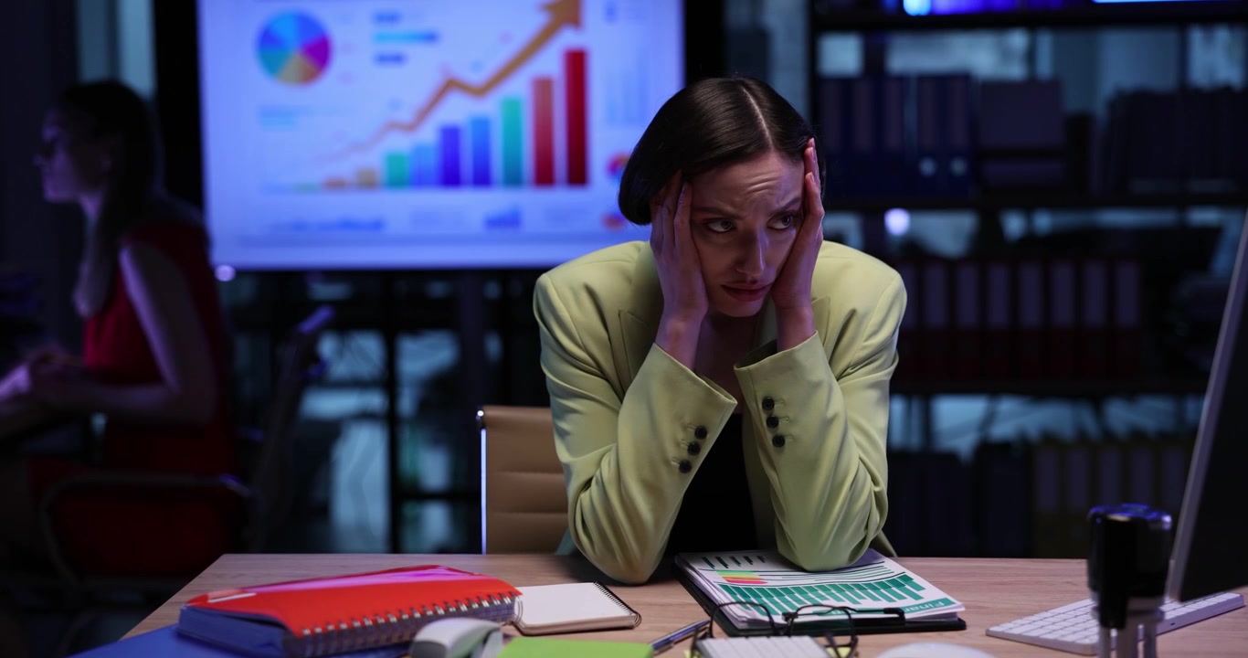 Stressed woman employee prepares reports working overtime