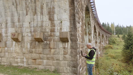 engineer inspecting an old stone railway bridge