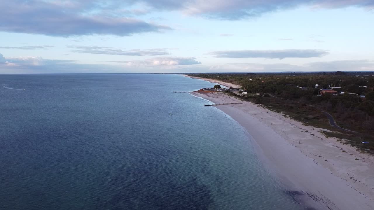 Vista aerea verso una rampa di alaggio con una piccola barca a motore diretta a riva al tramonto