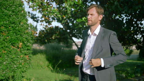 businessman adjusting suit in a park