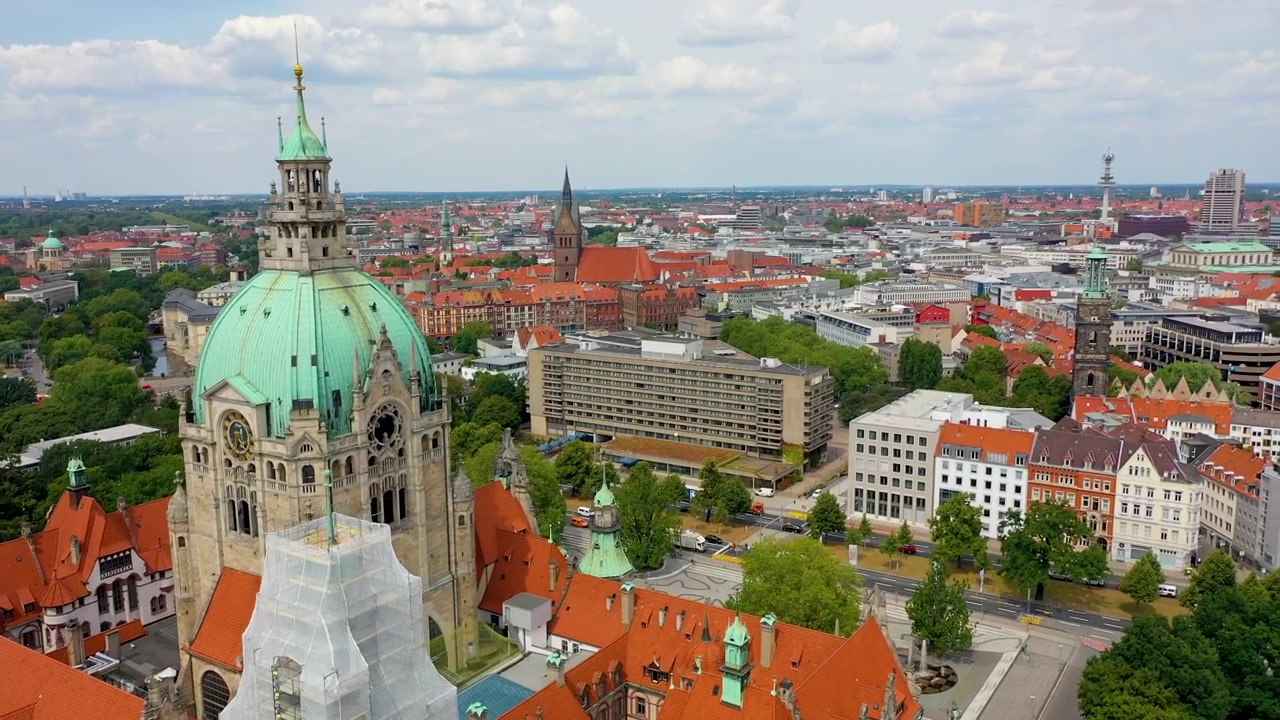 Cinematic aerial footage showcasing the impressive New City Hall Neues Rathaus and the surrounding urban landscape of Hanover, Germany.