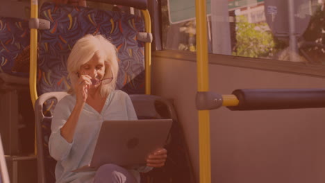 caucasian senior woman wearing her glasses and using laptop in the bus