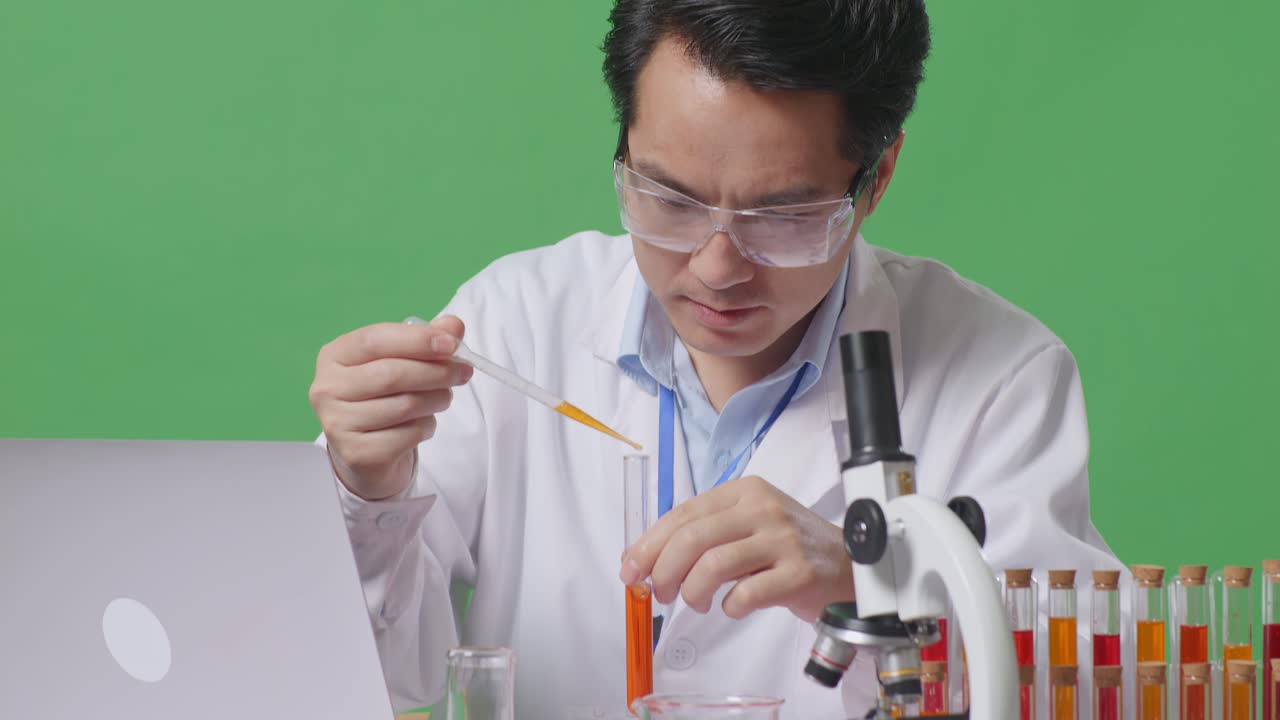 Close Up Of Asian Man Scientist Making Experiment With Test Tube And Typing On A Laptop Then Having A Headache On The Table With Microscope In The Green Screen Background Laboratory