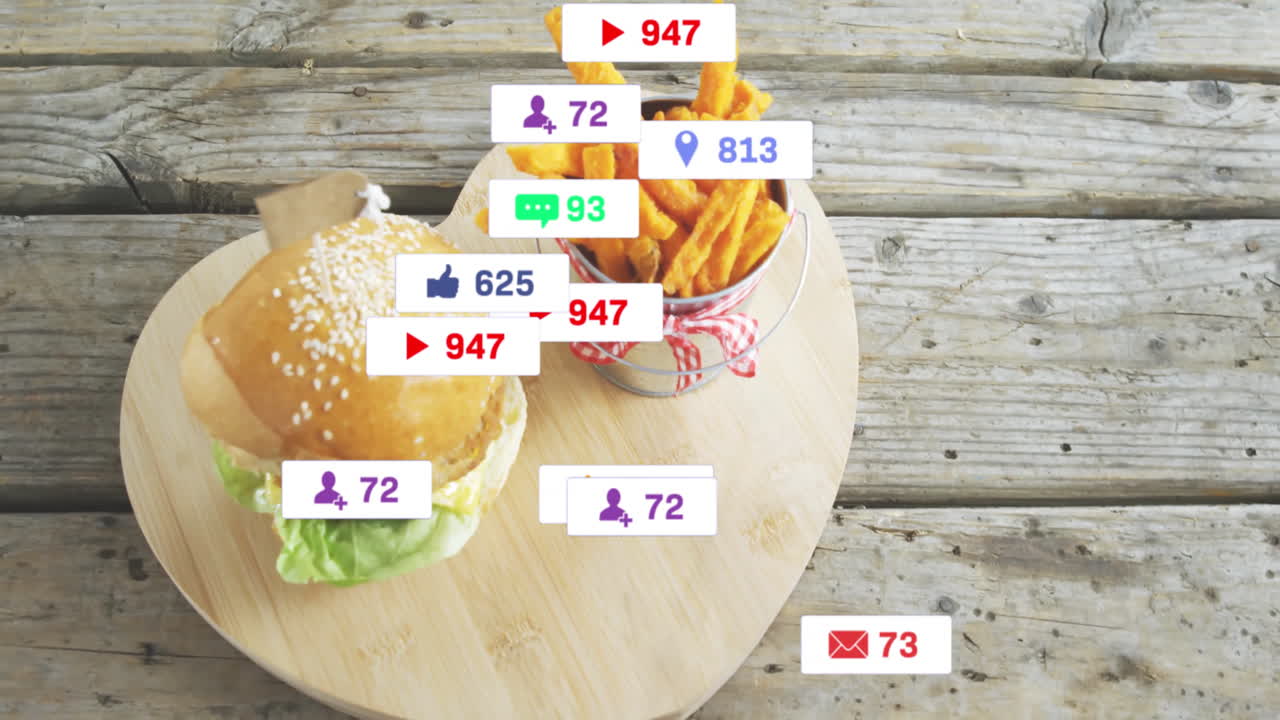 Burger and fries on wooden board with animation of social media icons overlay