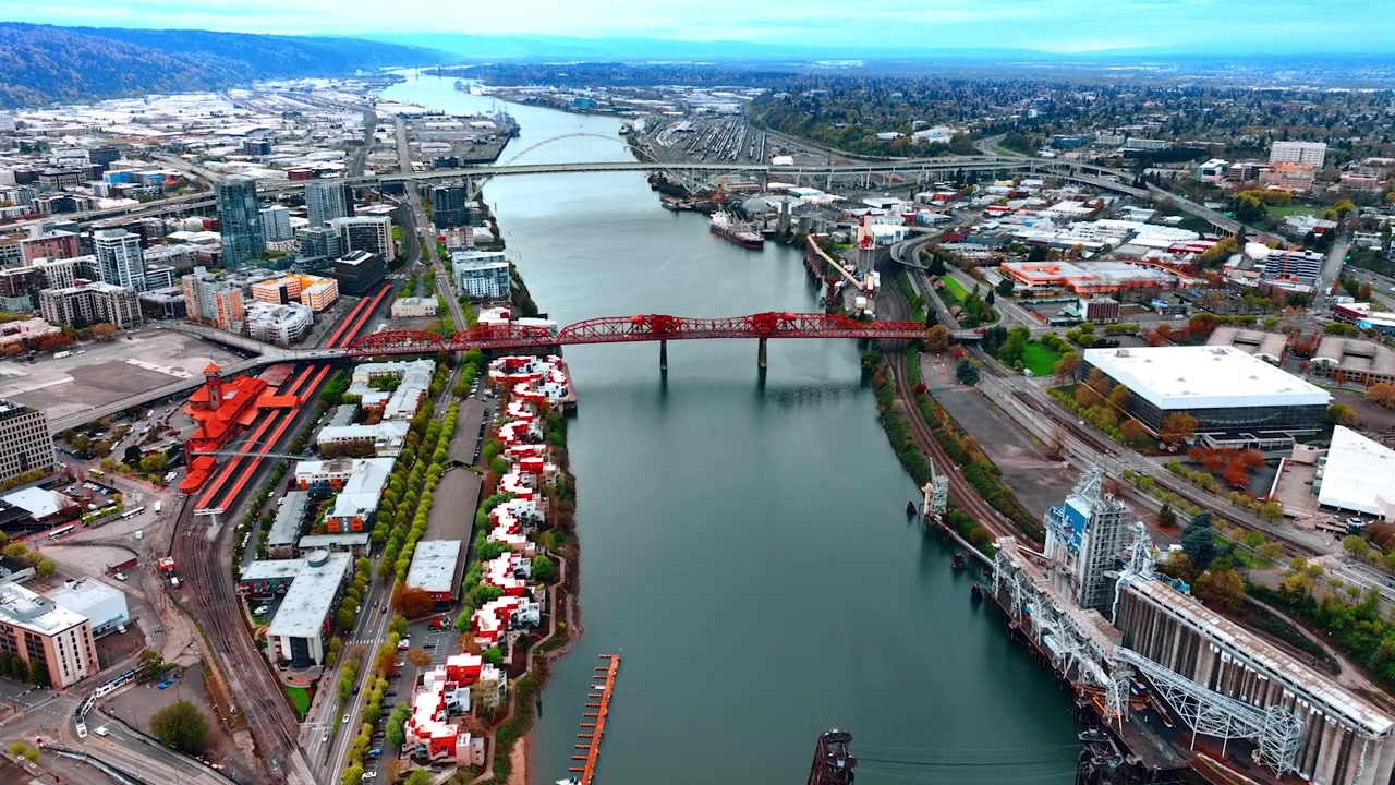 Volando sopra i ponti sul fiume Willamette a Portland, Oregon, USA. Vasto panorama della città con montagne e molto verde sullo sfondo