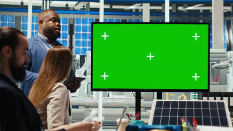 factory shareholders chat about company growth, looking at green screen monitor