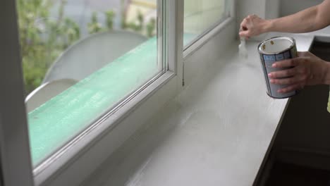 a woman paints a window with a brush